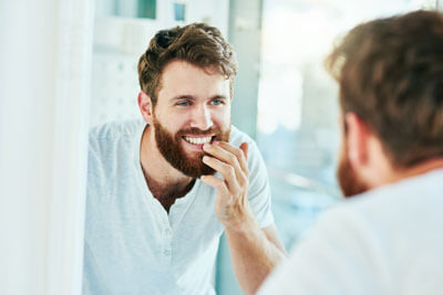 Man inspect his teeth in the mirror